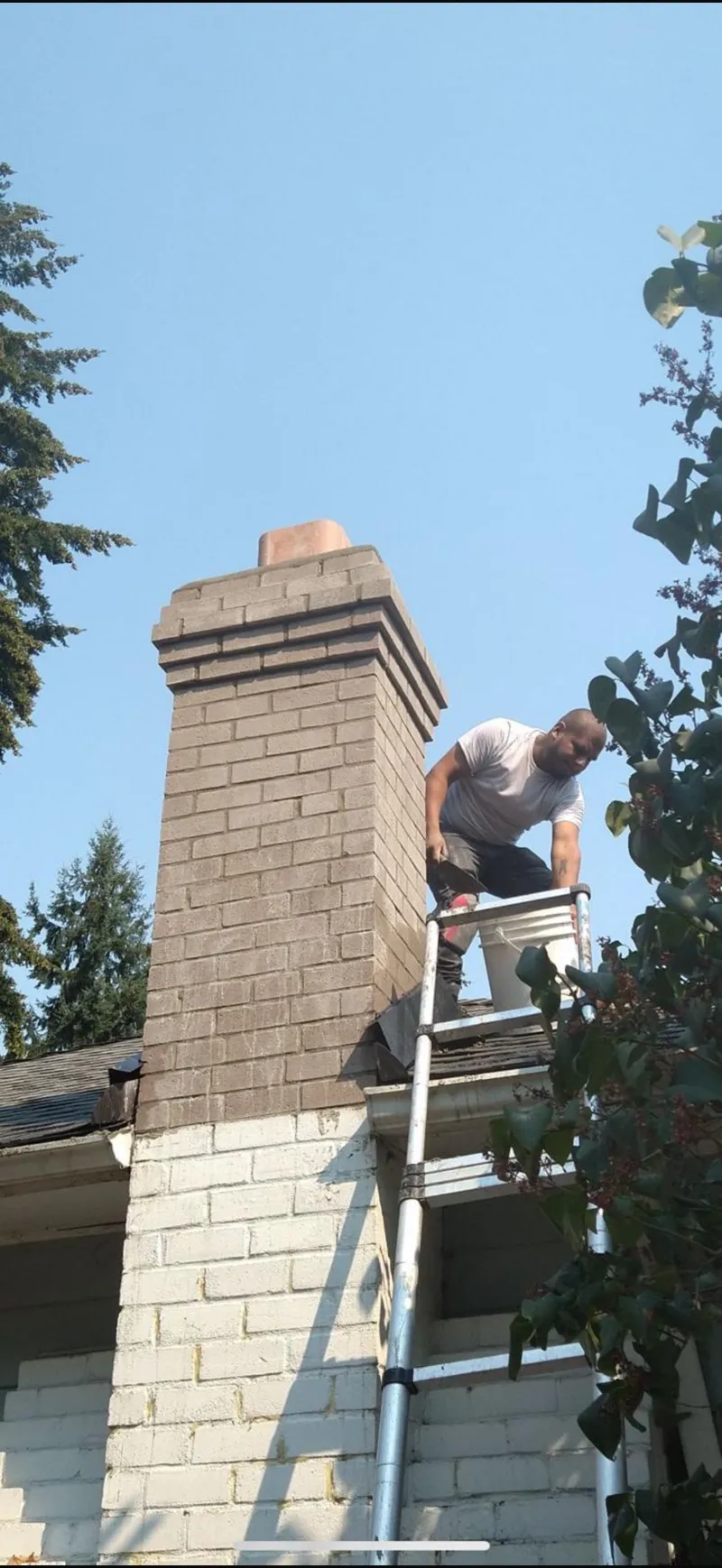Chimney repair technician working from a ladder